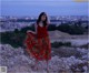 A woman in a red top and a floral skirt standing on a hill.