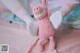 A pink stuffed animal sitting on top of a bed.