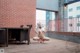 A naked woman sitting on a wooden deck next to a table.