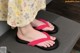 A woman wearing a pair of pink flip flops on a couch.