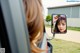 A woman is looking in the rear view mirror of a car.