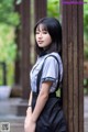 A woman leaning against a wooden pole in a park.