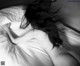 A black and white photo of a woman laying in bed.