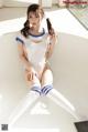 A woman in a white and blue outfit sitting on a white table.