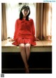 A woman in a red dress sitting on a window sill.