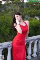 A woman in a red dress posing on a balcony.