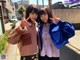 Two young women standing next to each other on a city street.