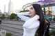 A woman with long black hair standing in front of a building.